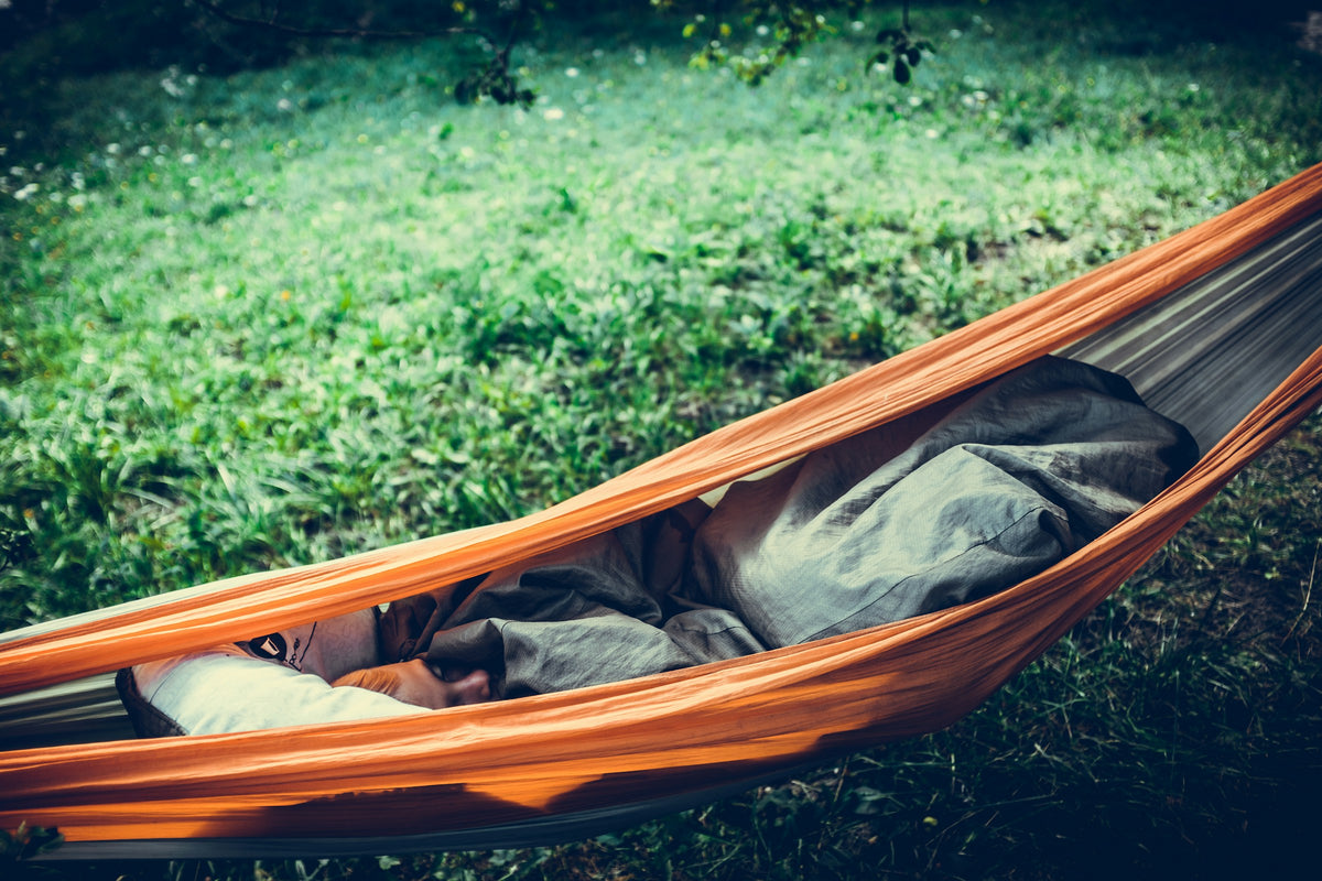 Person relaxing in an orange hammock outdoors
